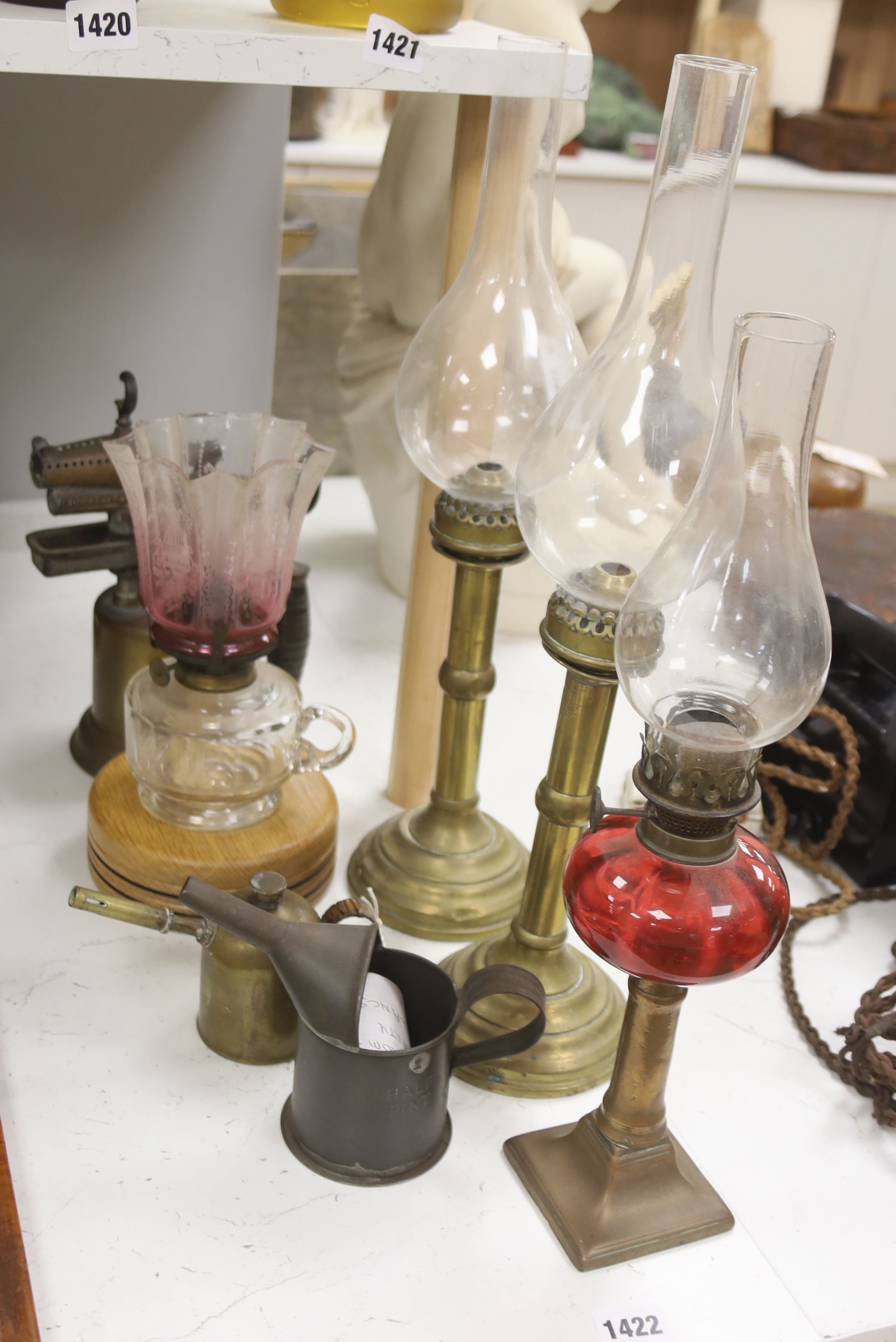 A pair of candle storm lamps, two oil lamps, a paint stripper, a jeweller's blow lamp and oil can, tallest 49cm